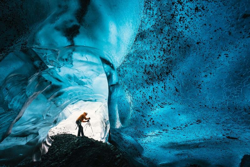 Wednesday 25th November 2015, Vatnajökull national park, Iceland: Photographer Mikael Buck with assistance from renowned local Icelandic guide Einar Runar Sigurdsson, explored the frozen world of Vatnajökull glacier in Iceland using Sony’s world first back-illuminated full-frame sensor – which features in the α7R II camera. His images were taken without use of a tripod or any image stitching techniques in photoshop. This was made possible through Sony’s new sensor technology, allowing incredibly detailed low-light hand held photography. Previously images this detailed would have required carrying bulky equipment to the caves, some of which can require hiking and climbing over a glacier for up to two hours to to access. This picture: Inside the 'ABC cave' - which stands for Amazing Blue Cave.  Guide Einar Runar Sigurdsson is seen taking a photo at the entrance to the cave PR Handout - editorial usage only. Photographer's details not to be removed from metadata or byline. For further information please contact Rochelle Collison at Hope & Glory PR on 020 7014 5306 or rochelle.collison@hopeandglorypr.com Copyright: © Mikael Buck / Sony 07828 201 042 / mikaelbuck@gmail.com